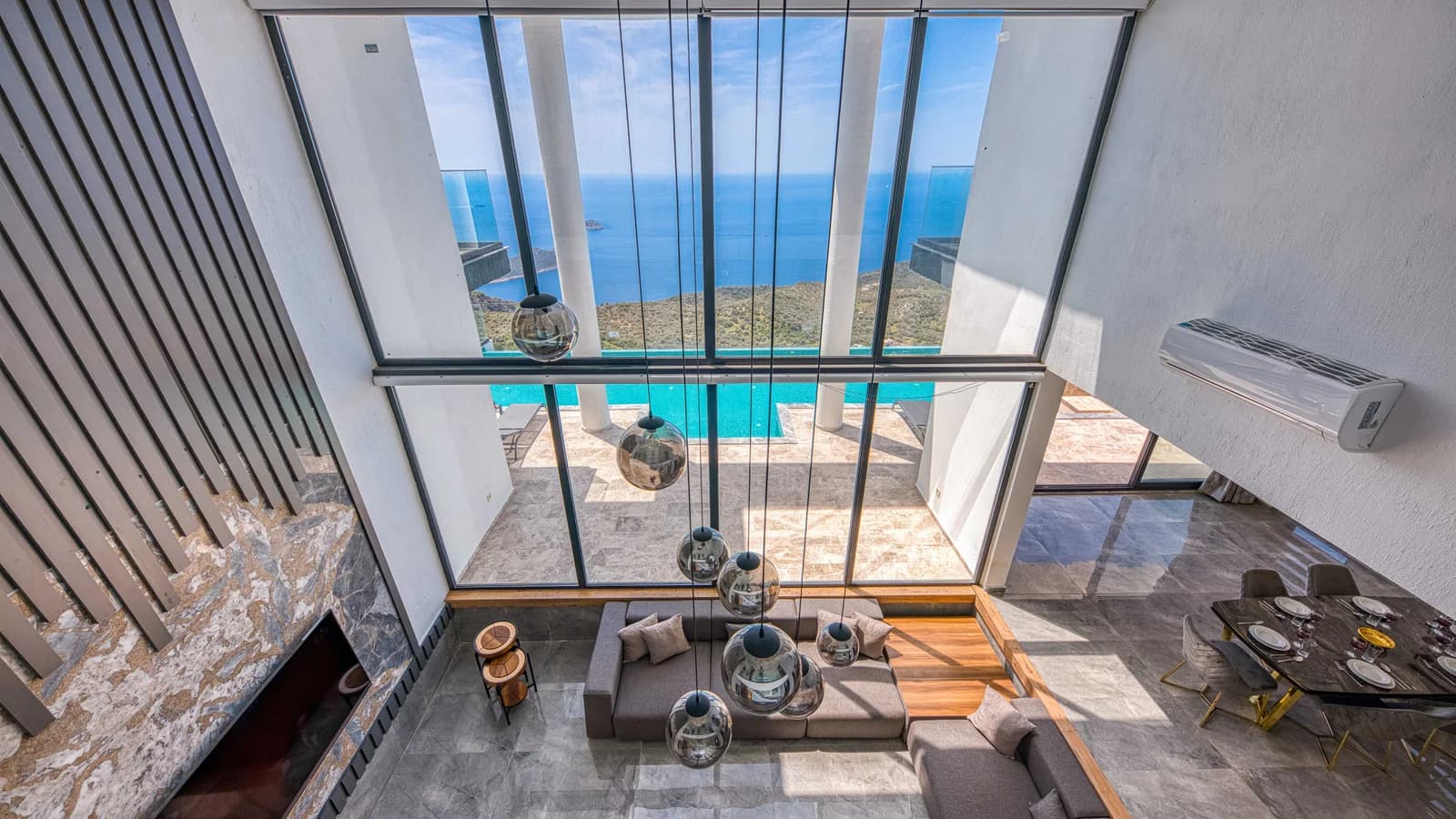A spacious modern villa living room with large windows overlooking the ocean.