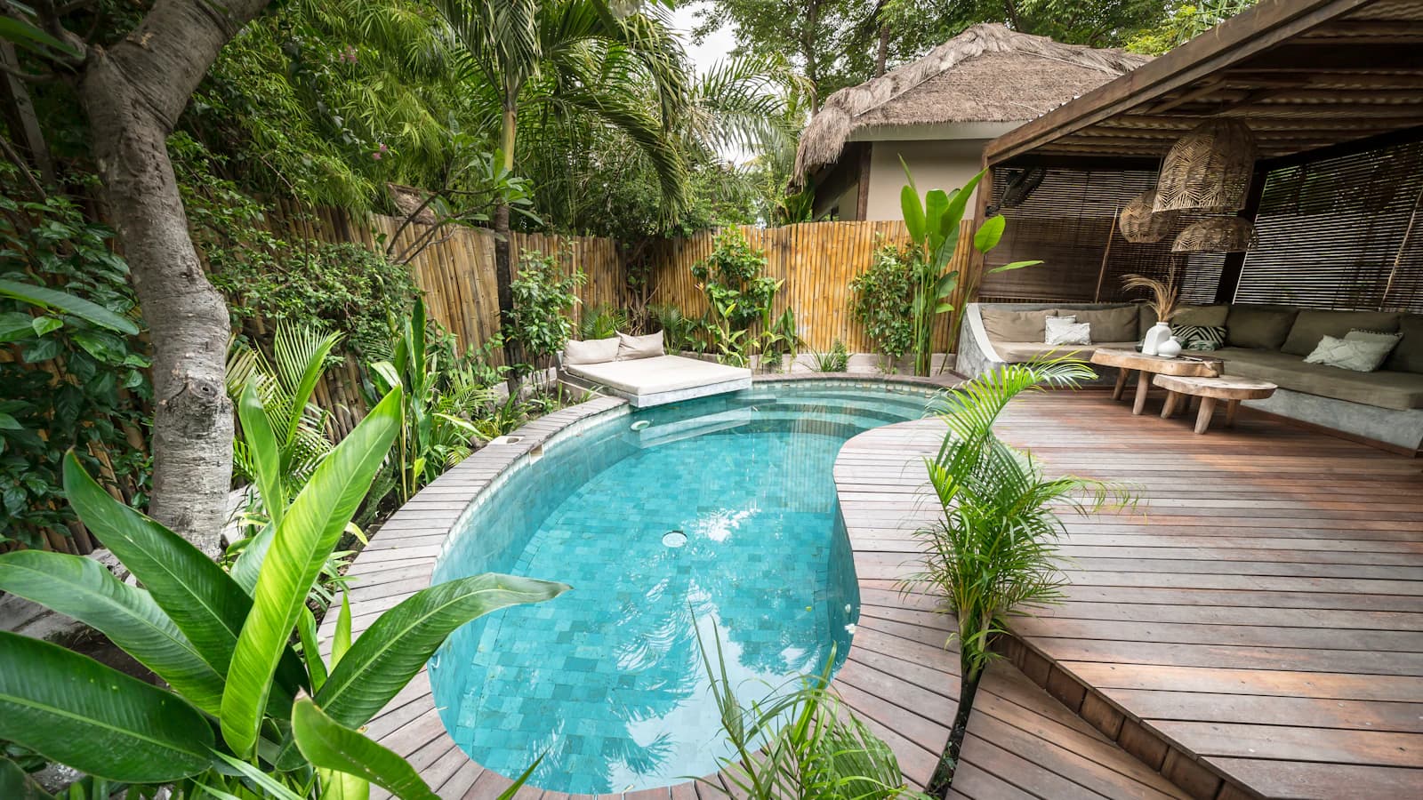 Private turquoise pool surrounded by tropical plants and a shaded villa terrace.